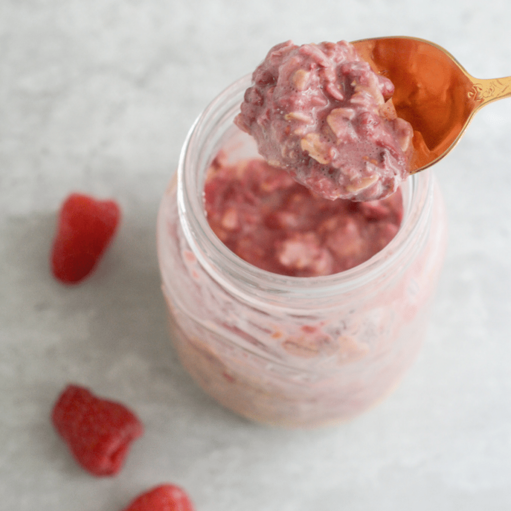 A close-up view of a spoonful of raspberry overnight oats.
